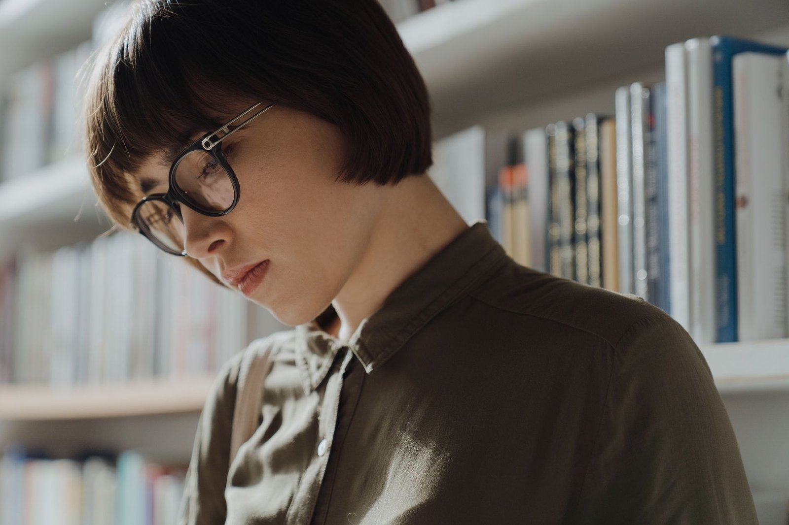 A woman in glasses reading in a library
