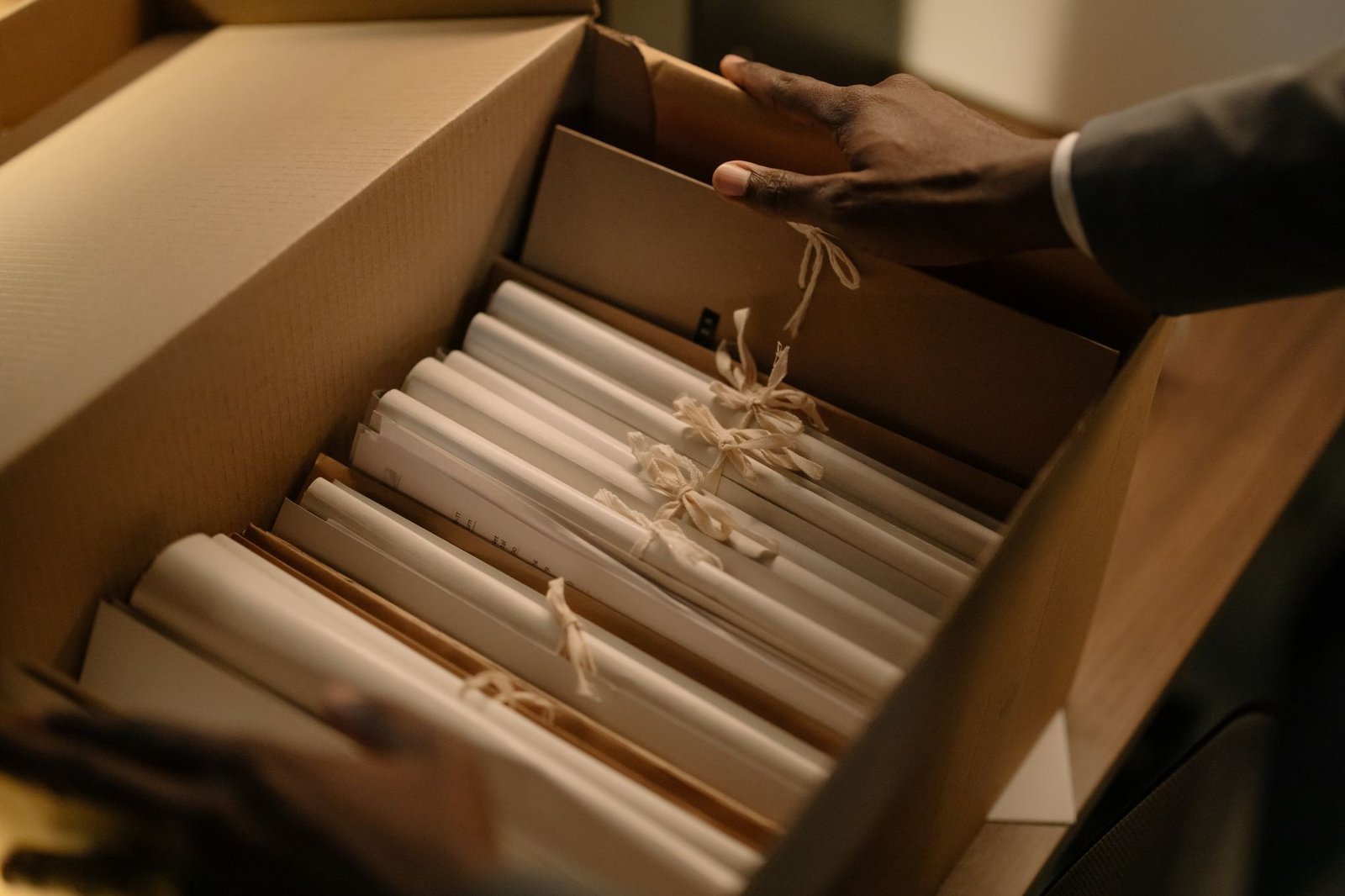 Hands sorting file folders in a box of archival records